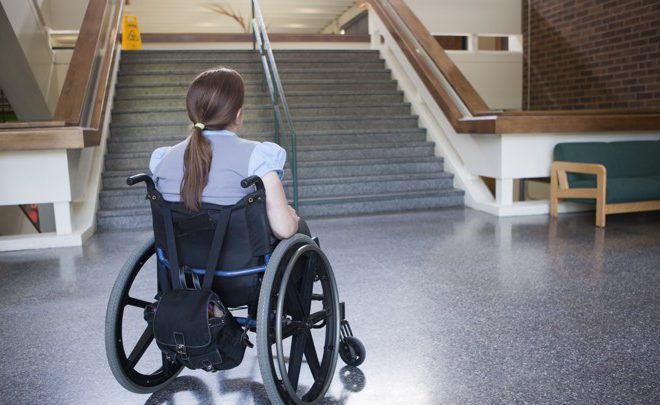 Woman with Spina Bifida in wheelchair studying difficulty of accessing stairway